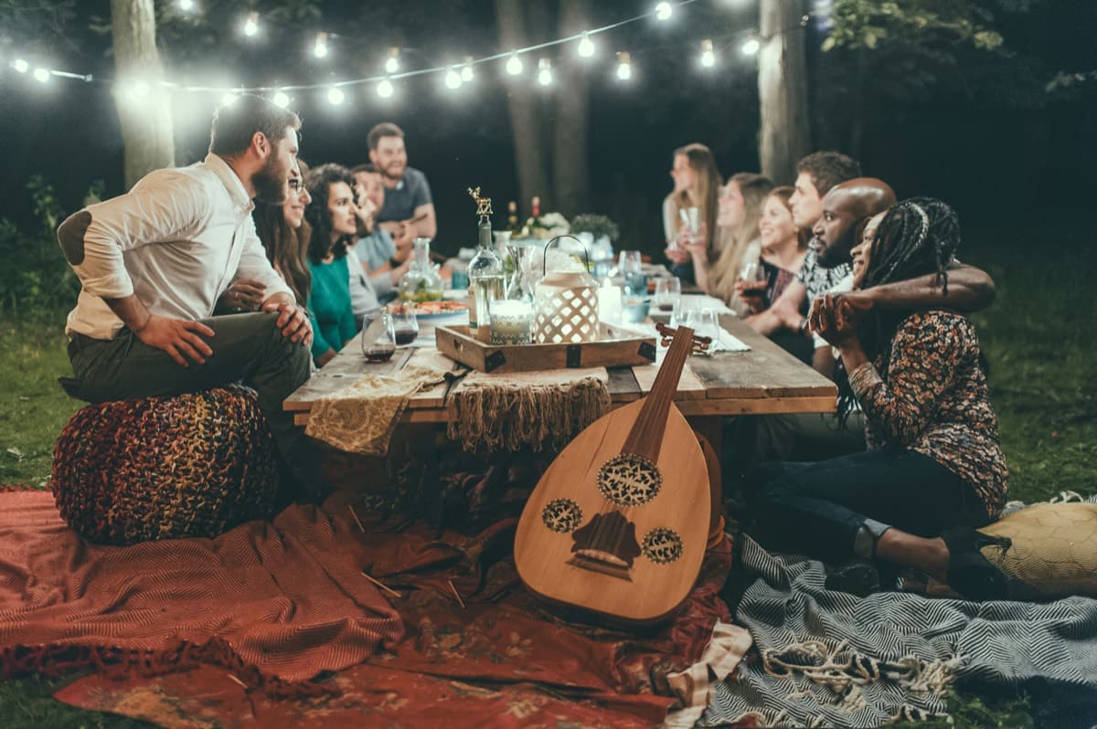 Un grupo de amigos comparte una cena al aire libre bajo luces colgantes.